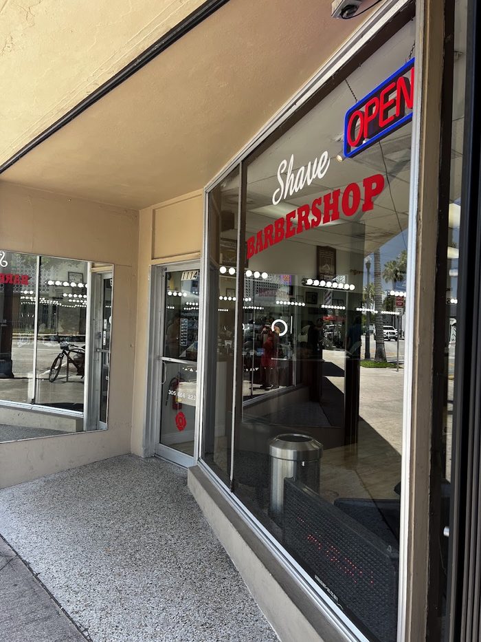 Entrada de Shave Barbershop con el letrero OPEN en el cristal